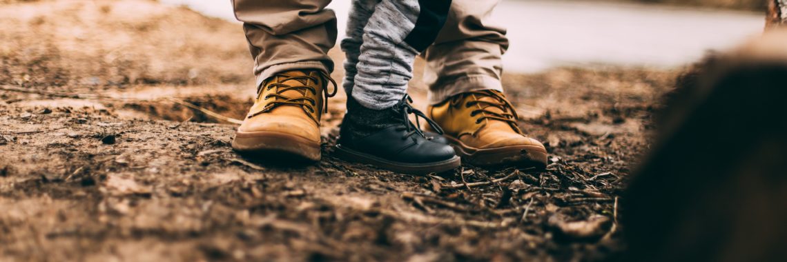 Photo by Daiga Ellaby via unsplash of adult and child wearing boots, standing on soil