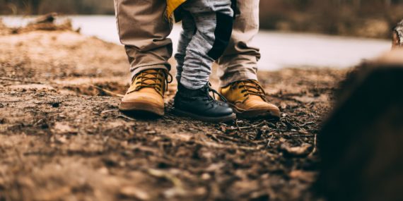 Photo by Daiga Ellaby via unsplash of adult and child wearing boots, standing on soil