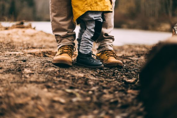 Photo by Daiga Ellaby via unsplash of adult and child wearing boots, standing on soil