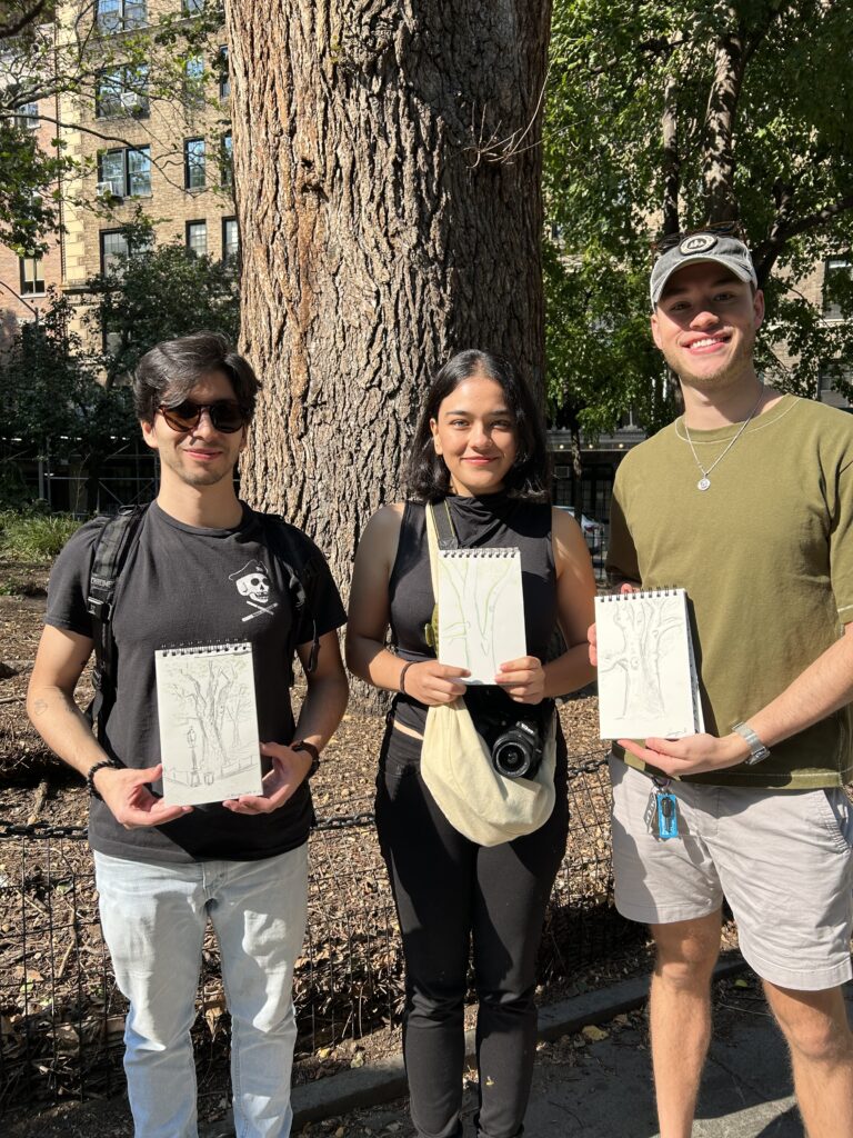 Three people standing in front of the English with their drawings on the elm, the oldest tree in Manhattan